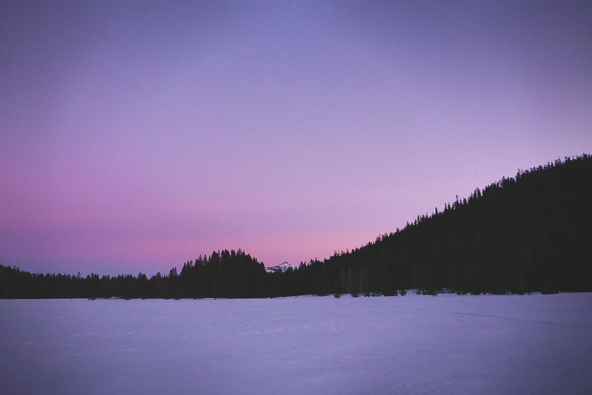 Purple haze over the sky and snow on a mountain lake